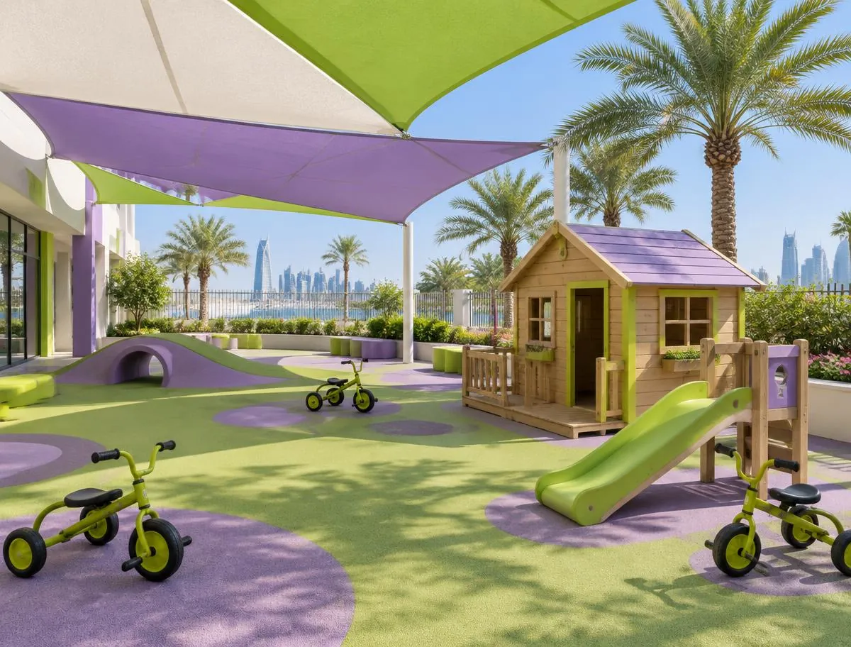 Shaded outdoor play area with sun sails, a wooden playhouse, a slide, tricycles and palm trees